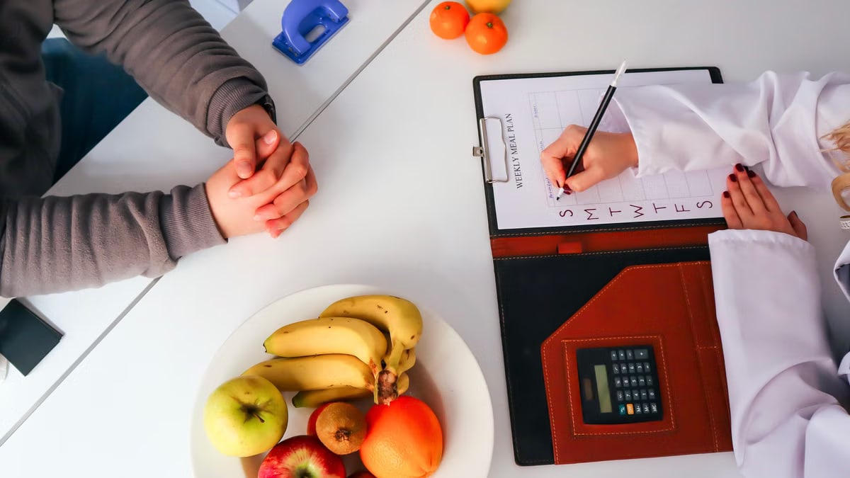 Top view of a dietitian planning a healthy diet with fresh fruits on the table, focusing on health and nutrition.